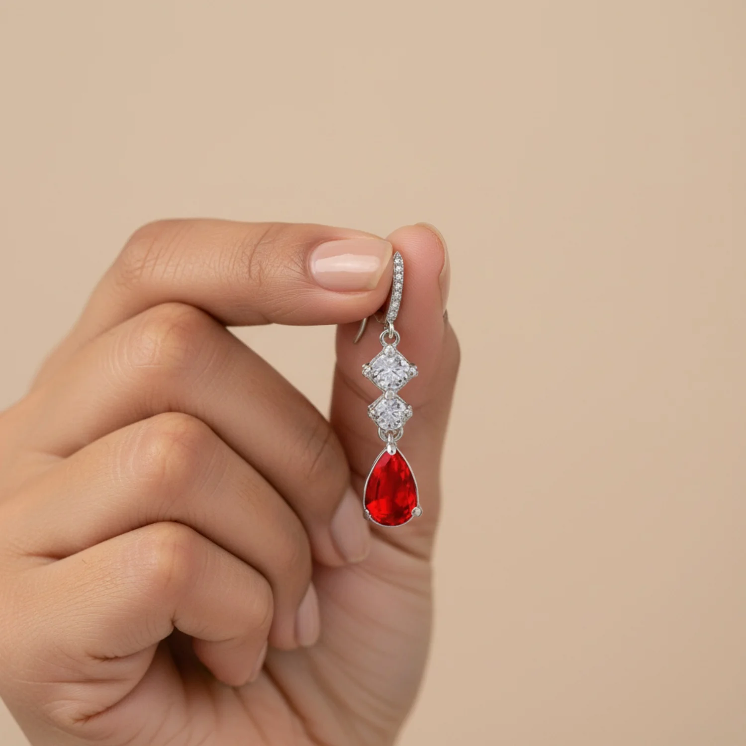 Hand holding a ruby and diamond drop earring